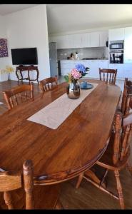 une grande table en bois avec des chaises et une cuisine dans l'établissement Rare GEM in Westgate, à Auckland
