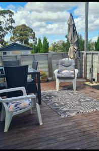 un patio con sillas y una sombrilla en una terraza en Rare GEM in Westgate en Auckland