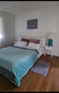 1 dormitorio con 1 cama grande con manta azul en Rare GEM in Westgate en Auckland