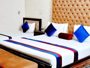 Calming Residence في لاهور: سريرين في غرفة الفندق مع وسائد زرقاء وحمراء