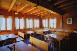 een restaurant met houten tafels, stoelen en ramen bij Glatzl Trahütten Alm in Sankt Lorenzen am Wechsel
