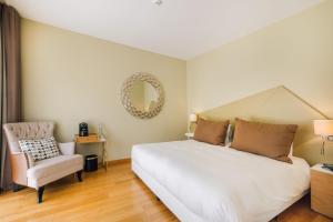 1 dormitorio con cama, silla y espejo en Alva Valley Hotel, en Oliveira do Hospital