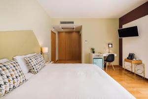 um quarto com uma grande cama branca e uma secretária em Alva Valley Hotel em Oliveira do Hospital