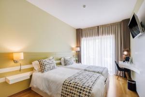 um quarto de hotel com uma cama e uma televisão em Alva Valley Hotel em Oliveira do Hospital