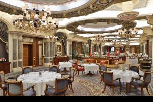 un restaurant avec des tables, des chaises et des lustres blancs dans l'établissement The Ritz-Carlton Jeddah, à Djeddah