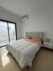 - une chambre blanche avec un grand lit et une fenêtre dans l'établissement joli appartement a jardin de Carthage, à Tunis