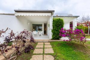 uma casa branca com um pátio e flores roxas em Villa Buganvillea near the beach em Maracalagonis