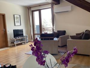 a living room with a couch and a table with purple flowers at Cozy Mountain Apartment in Borovets