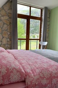 Schlafzimmer mit einem rosa Bett und einem großen Fenster in der Unterkunft Petriti theth in Theth