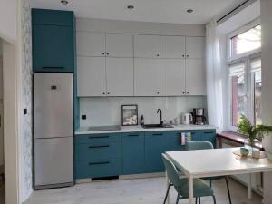 une cuisine avec des placards bleus et blancs et une table dans l'établissement Przytulne mieszkanie w kamienicy, à Radomsko