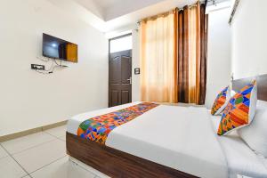 - une chambre avec un lit et une télévision dans l'établissement FabHotel KRB Paradise, à Dehradun