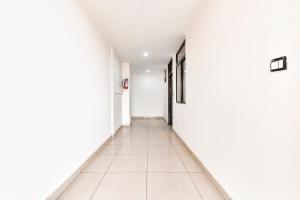 an empty corridor with white walls and white tile floors at FabHotel KRB Paradise in Dehradun