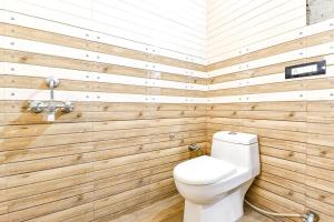 a bathroom with a toilet and wooden walls at FabHotel KRB Paradise in Dehradun
