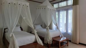 2 Betten mit weißen Vorhängen in einem Schlafzimmer in der Unterkunft Hôtel La Belle Etoile in Labuan Bajo
