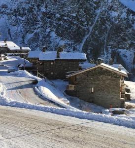 een groep gebouwen bedekt met sneeuw voor een berg bij Chalet Epilobe - pied des pistes - vue magnifique in Montvalezan