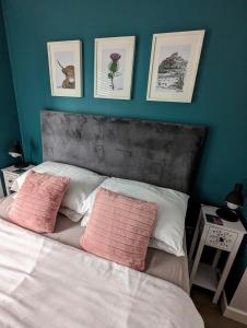um quarto com uma cama com duas almofadas cor-de-rosa em Cosy guest room in a family home em Edimburgo