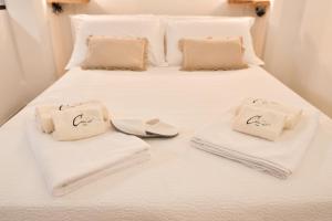 un letto bianco con asciugamani e pantofole di Civico 60 Apartments a Ceglie Messapica