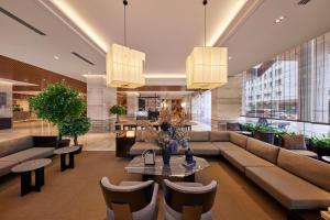 a lobby with a couch and a table and chairs at Hotel Royal Signature in Kuala Lumpur