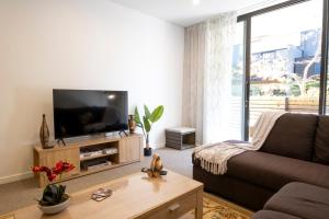 a living room with a couch and a flat screen tv at Modern, Ground floor , CBD, Free parking, 2-3 Beds in Christchurch