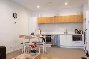 a kitchen with white cabinets and a table with chairs at Modern, Ground floor , CBD, Free parking, 2-3 Beds in Christchurch
