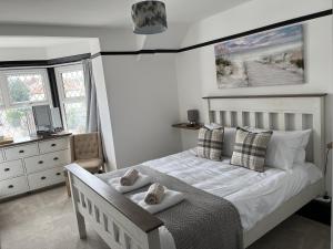 a bedroom with a white bed and a dresser and windows at The Fishmongers Tavern in Sheringham