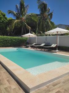 a swimming pool with two chairs and umbrellas at Résidence Ahitantsoa Majunga in Mahajanga