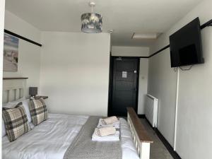 a bedroom with a bed and a flat screen tv at The Fishmongers Tavern in Sheringham