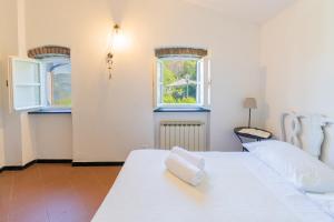 1 dormitorio con 2 camas blancas y 2 ventanas en La Casetta del Casale In Vigna, CinqueTerreCoast, en Casarza Ligure