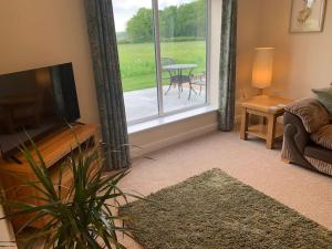 a living room with a couch and a television and a table at Woodside Retreat with Luxury Hot Tub in Retford
