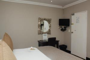 1 dormitorio con cama, espejo y escritorio en Oaklands inn and Conference Centre, en Johannesburgo
