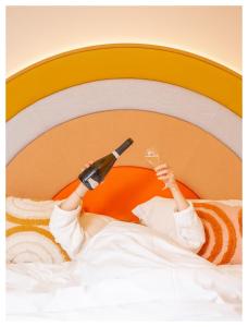 eine Person, die mit einer Flasche Wein im Bett liegt in der Unterkunft Nice Pam Hotel Fully Renovated in Nizza