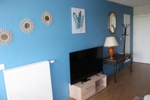 uma sala de estar com uma parede azul e uma televisão de ecrã plano em Appartement Cosy Proche Disneyland - tout Confort em Chessy