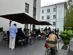 um grupo de pessoas sentadas em mesas sob um guarda-chuva em City Park Hotel by CHM em Bila Tserkva
