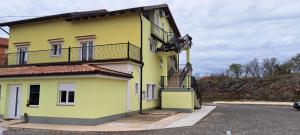 a yellow building with a balcony on the side of it at Apartman Emily in Čavle