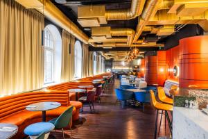里加的住宿－Tribe Riga City Center，一间设有橙色和蓝色椅子及桌子的餐厅