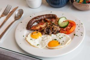 un plato de desayuno con huevos, salchichas y tomates en El Dorado Hotel and Self Catering en Oudtshoorn