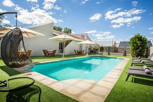 a swimming pool with a swing in a yard at El Dorado Hotel and Self Catering in Oudtshoorn