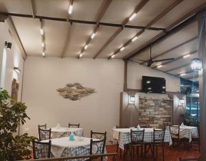 a dining room with tables and chairs and a tv at Ενοικιαζόμενα Δωμάτια "Pelion Plaza" in Agios Ioannis Pelio