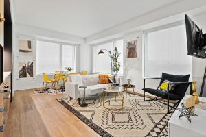 a living room with white furniture and yellow chairs at Boston Cambridge Suites Family Edition by Orchard in Cambridge