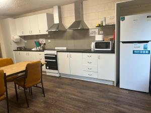 a kitchen with white cabinets and a table and a refrigerator at green gables warburton student camper accomodation in Warburton