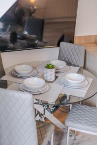 uma mesa de jantar em vidro com pratos e cadeiras brancas em Peterhead Stay - SJA Stays - Modern 2 Bed Apartment em Peterhead