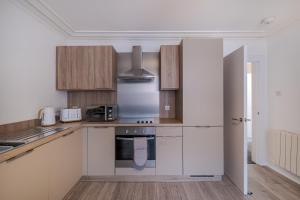 uma cozinha com armários brancos e um frigorífico em Peterhead Stay - SJA Stays - Modern 2 Bed Apartment em Peterhead