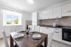 cocina con mesa de madera y armarios blancos en Apartment Viki, en Dubrovnik