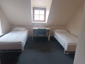 Zimmer mit 2 Betten, einem Tisch und einem Fenster in der Unterkunft Hotel - Bar Grafaite in Šiauliai