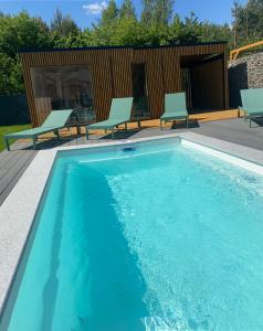 - une piscine avec 2 chaises et une terrasse dans l'établissement Leśna Polana Domki, à Okuninka