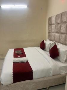 a large bed with red and white pillows on it at Hotel Kaushambi Grand in Ghaziabad