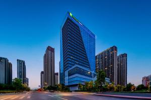 南京南京滨江智选假日酒店的黄昏时分城市中的一座高大的玻璃建筑