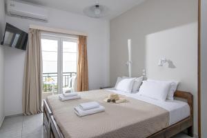 - une chambre avec un grand lit et des serviettes dans l'établissement Litsa Mare Apartments, à Agia Pelagia