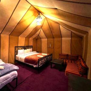a room with a bed and a table in a tent at desert indigo luxury camp in Merzouga