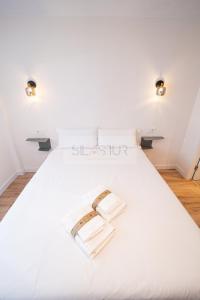 a white bed with two books on it at Sella Apartamento in Gijón
